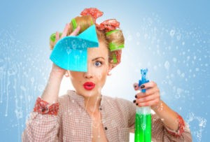 A woman with curlers on her head holding a spray bottle and rag.