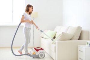 A woman is vacuuming in the living room