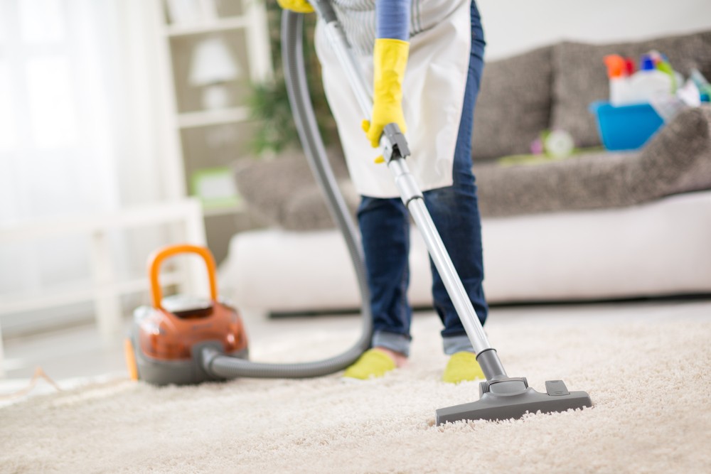 A person vacuuming the floor with a vacuum cleaner.