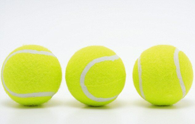 Three tennis balls are lined up in a row.