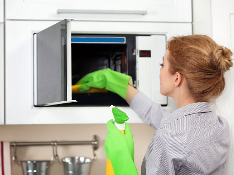 A woman cleaning the inside of an oven.