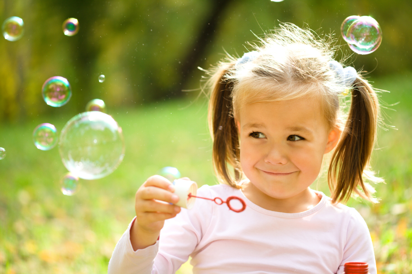 A little girl with pigtails holding a pair of scissors.