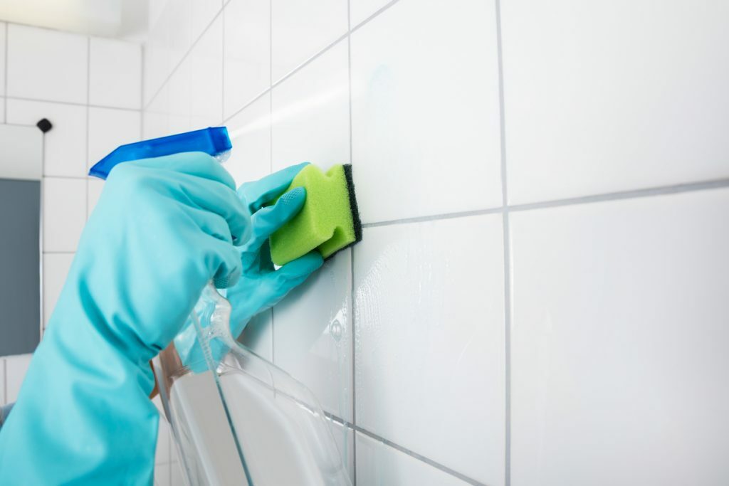 A person wearing gloves and cleaning the wall with a sponge.