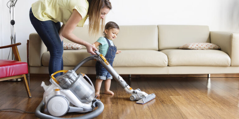 A woman and child are vacuuming the floor.