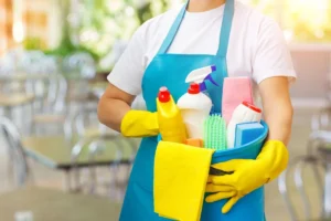 A person holding cleaning supplies in their hands.