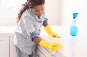 A woman in yellow gloves cleaning the counter.