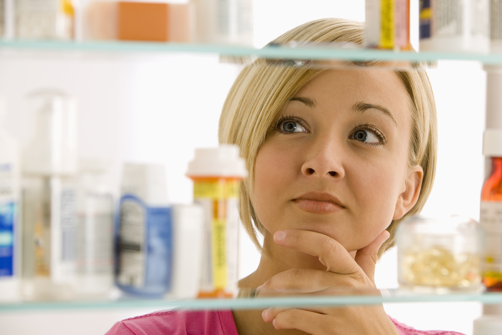 A woman looking in the mirror at medicine.