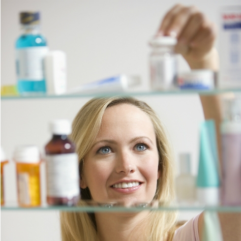 A woman is looking through the medicine shelf.