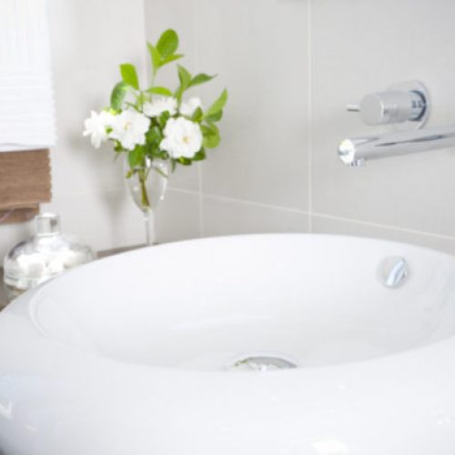 A white sink with flowers in the background.