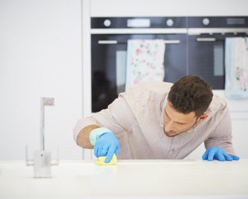 Man cleaning counters A man in blue gloves cleaning the counter.