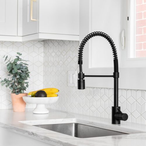 A farmhouse kitchen sink detail shot with a black faucet, mosaic A farmhouse kitchen sink detail shot with a black faucet, mosaic